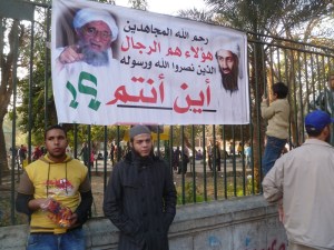 Around 5pm, the police relented and allowed the protestors to advance and demonstrate in front of the embassy, though the police presence guarded it and otherwise surrounded them. Graffiti and other banners were hung in the area, this one across the street on the wall of the Giza Zoo. Pictured are Osama bin Laden and Mohamed's brother Ayman. The sign reads: God have mercy on the jihadists. They are the men who gave victory to God and his prophet. Where are you?!