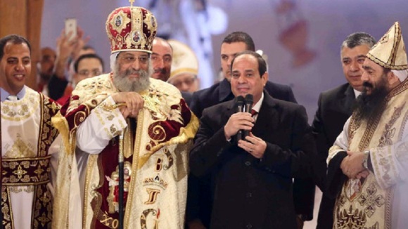 Egyptian President Sisi talks next to Coptic Pope Tawadros II as he attends Christmas Eve Mass at St. Mark's Cathedral in Cairo