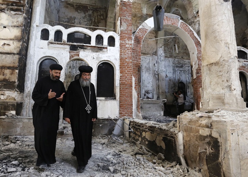 Bishop-General Macarius, a Coptic Orthodox leader, walks around the burnt and damaged Evangelical Church in Minya governorate